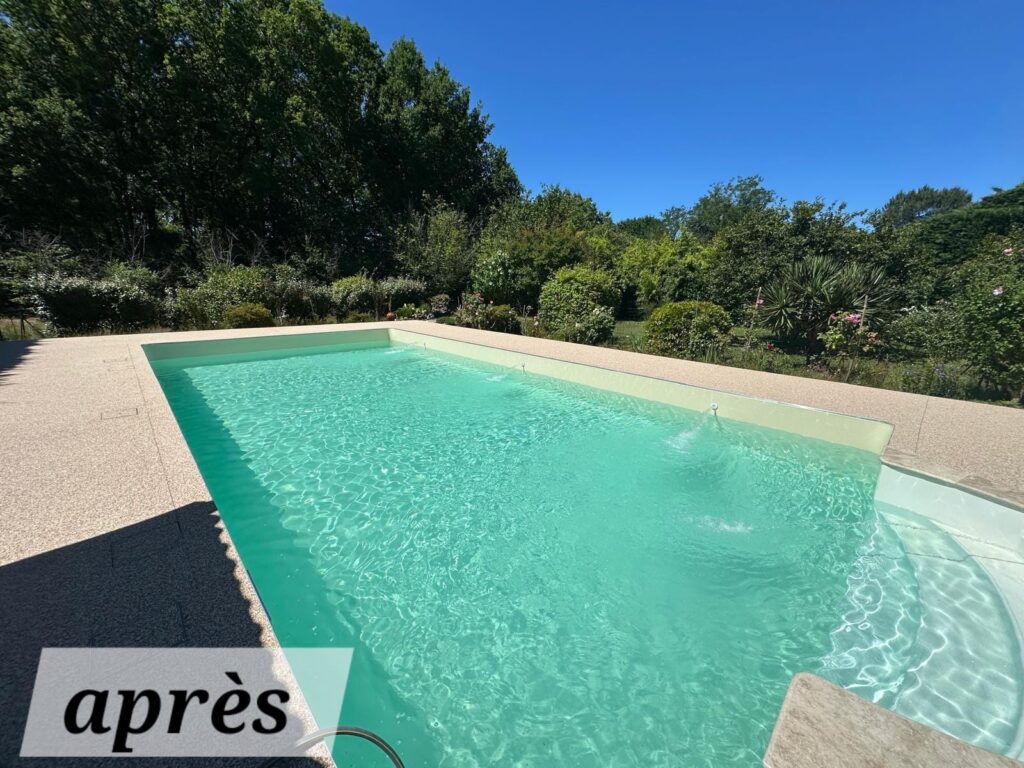 Piscine rénovée avec eau turquoise claire, terrasse en agrégats exposés, entourée de végétation luxuriante sous un ciel bleu. Texte visible : après.