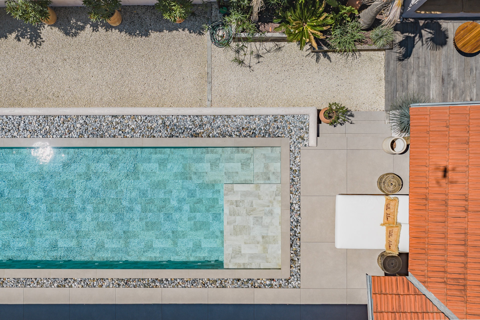 Piscine de luxe Villa Alma vue du ciel avec terrasse Vue aérienne d'une piscine moderne avec carrelage clair, transat Villa Alma et toit en terre cuite.